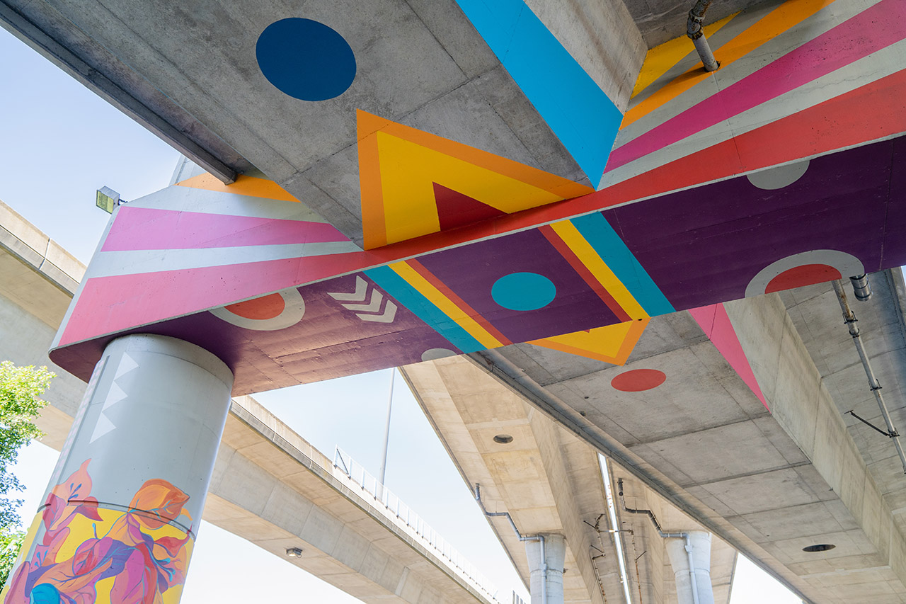 A mural features colorful geometric shapes and flowers underneath I-93, at Underground at Ink Block.