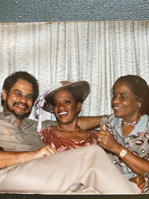 A picture of a printed photo shows three people sitting together, posing happily.