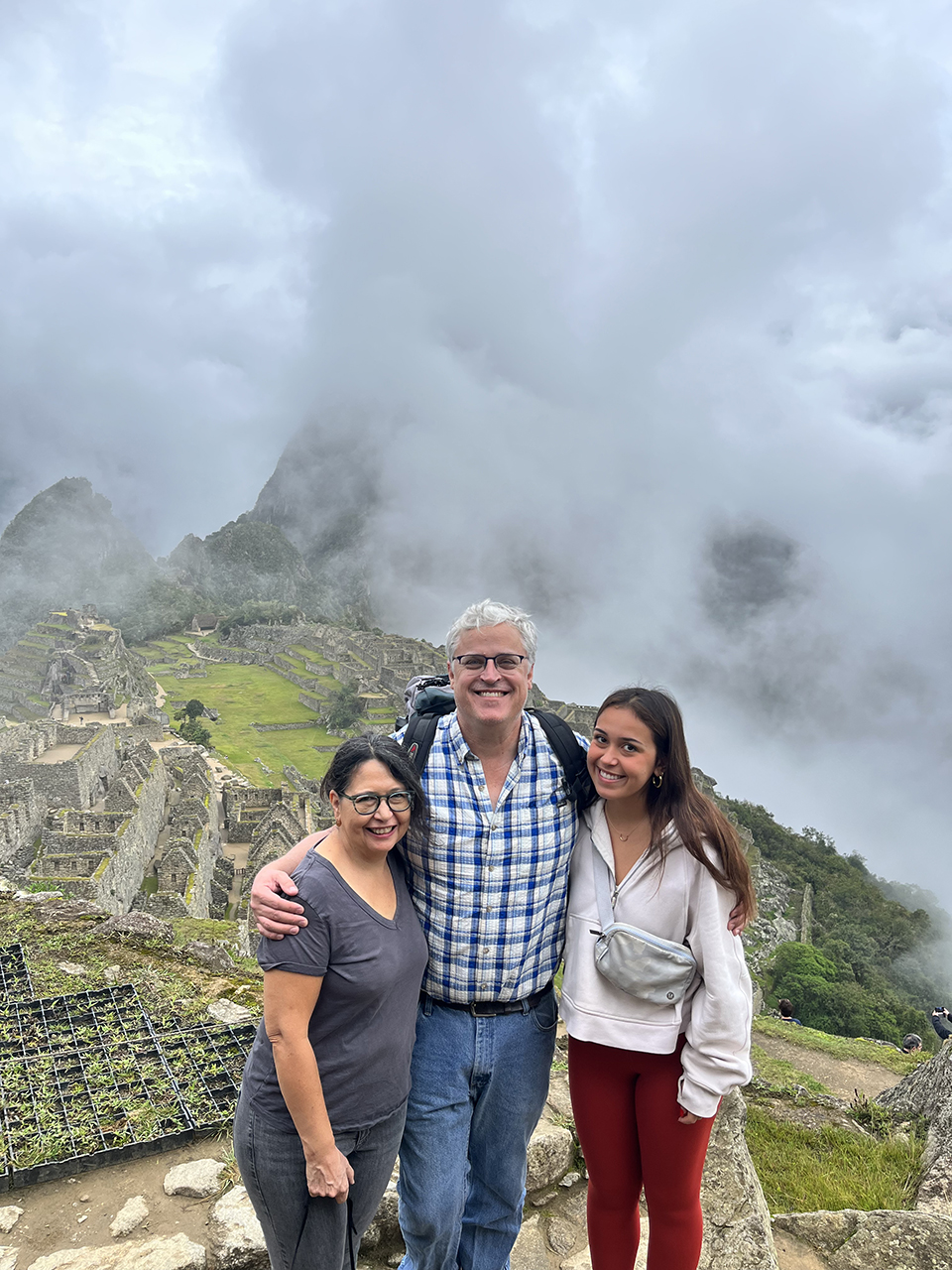 A family of three pose together against a misty mountain background.