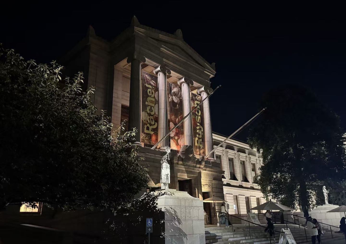 The Museum of Fine Arts Boston illuminated at night, with exhibition banners hanging from the columns.